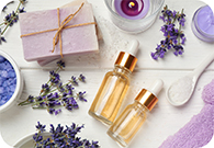 Bottles of lavender oil with lavender flower buds, soaps, candles, and bath salt